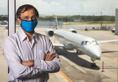 Computer scientist Ashok Srinivasan masked in front of a plane Computer scientist Ashok Srinivasan masked in front of a plane